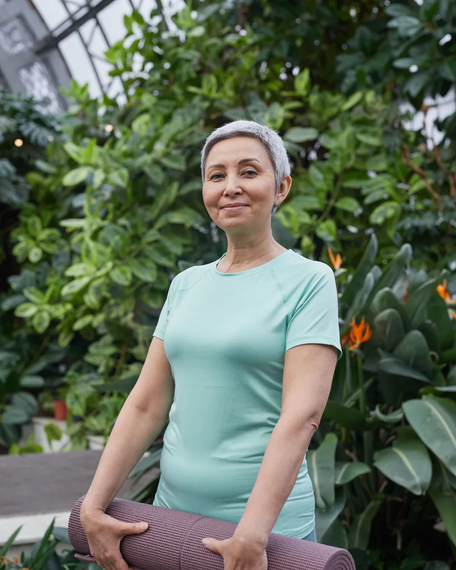Healthy, active woman in her fifties holding a yoga mat, representing bioidentical hormone replacement therapy patients at Embody Wellness in Folsom, California